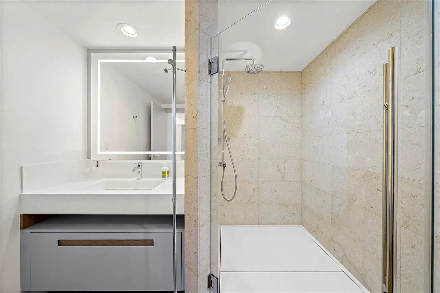 Baño reformado de Icon South Beach Apartment con mueble integrado, espejo iluminado y ducha abierta