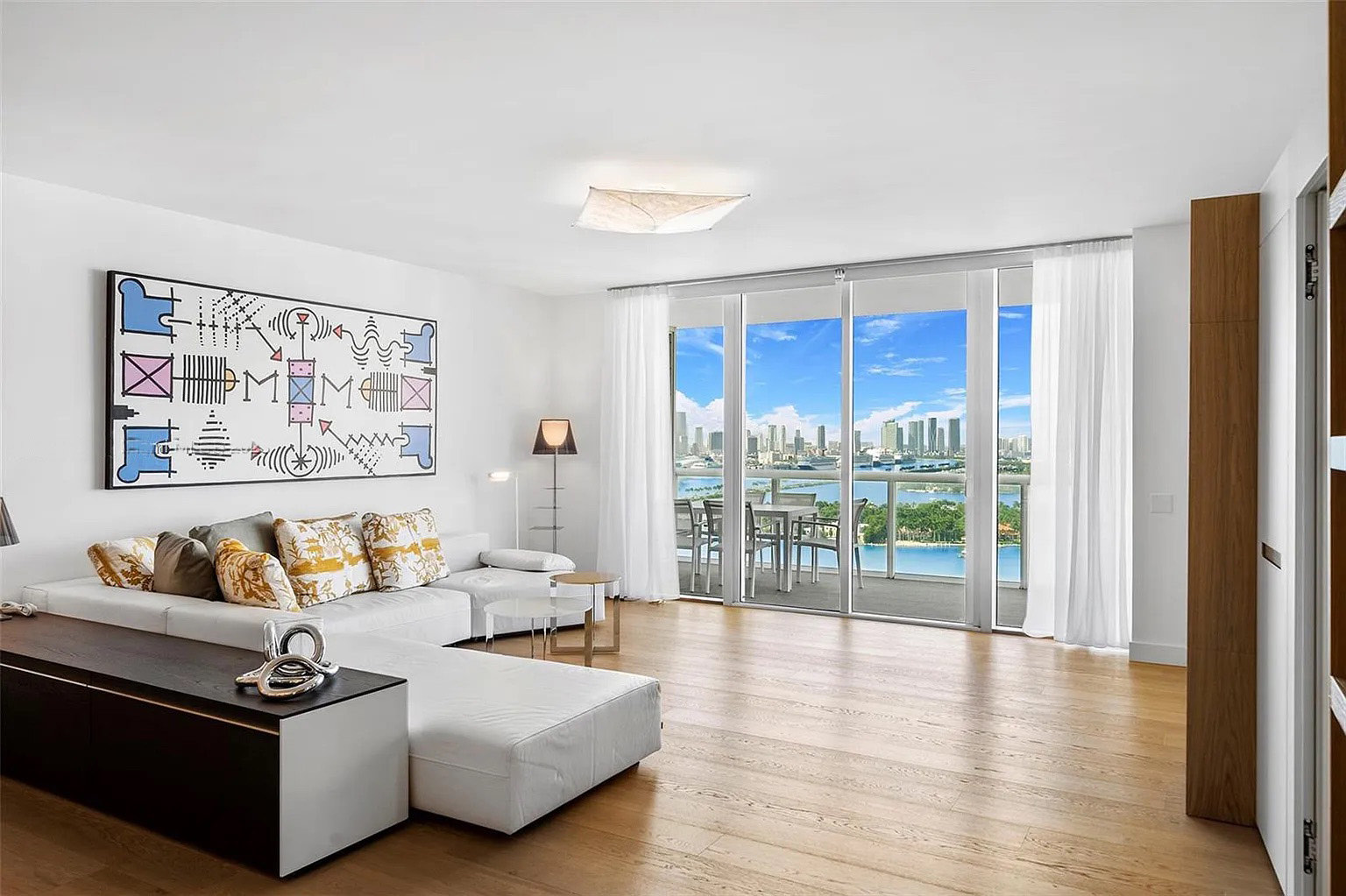 Salón de Icon South Beach Apartment con madera cálida y vistas al skyline desde el waterfront