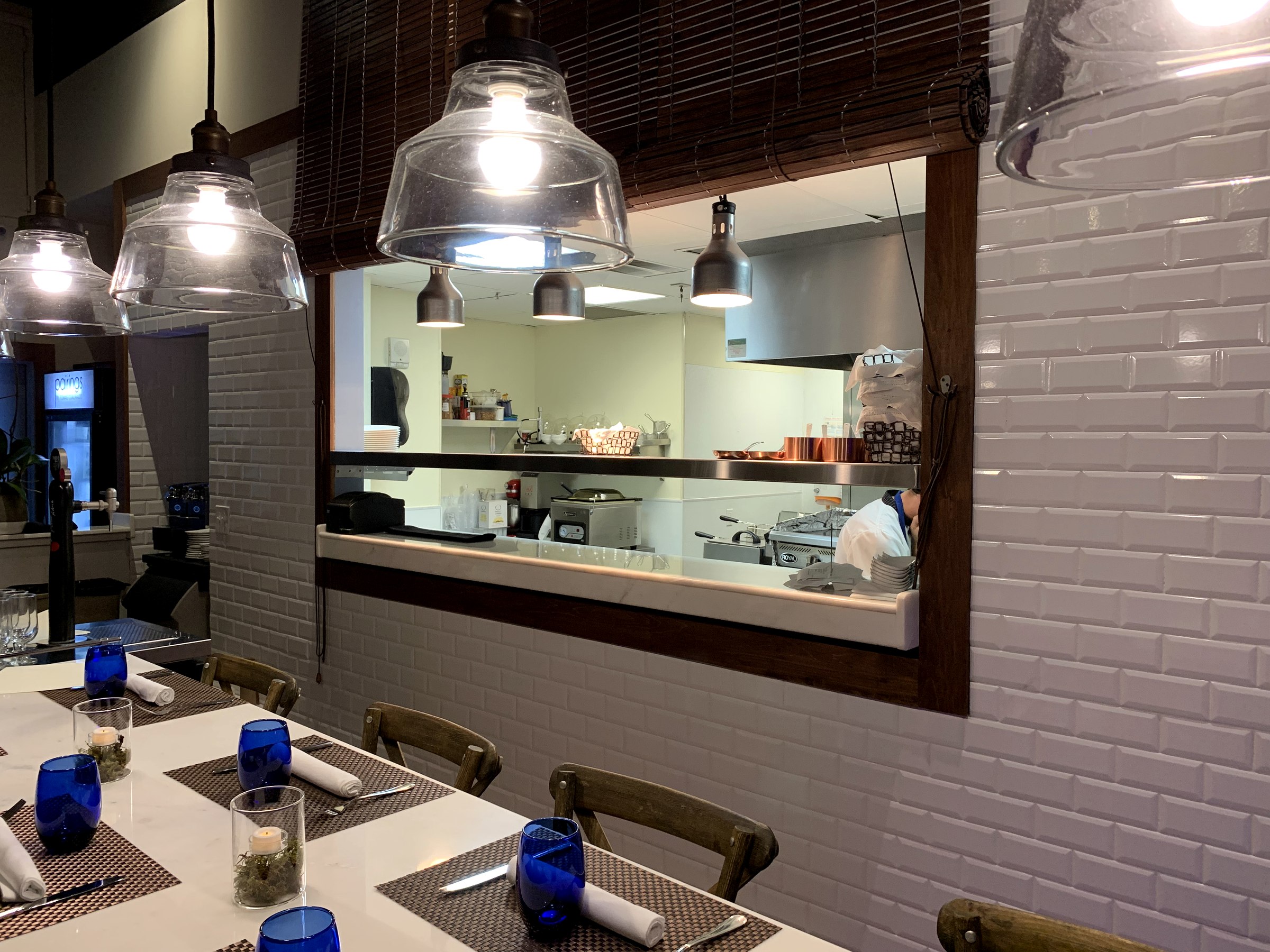 Cocina abierta enmarcada por madera y azulejo blanco en Pairings Restaurant