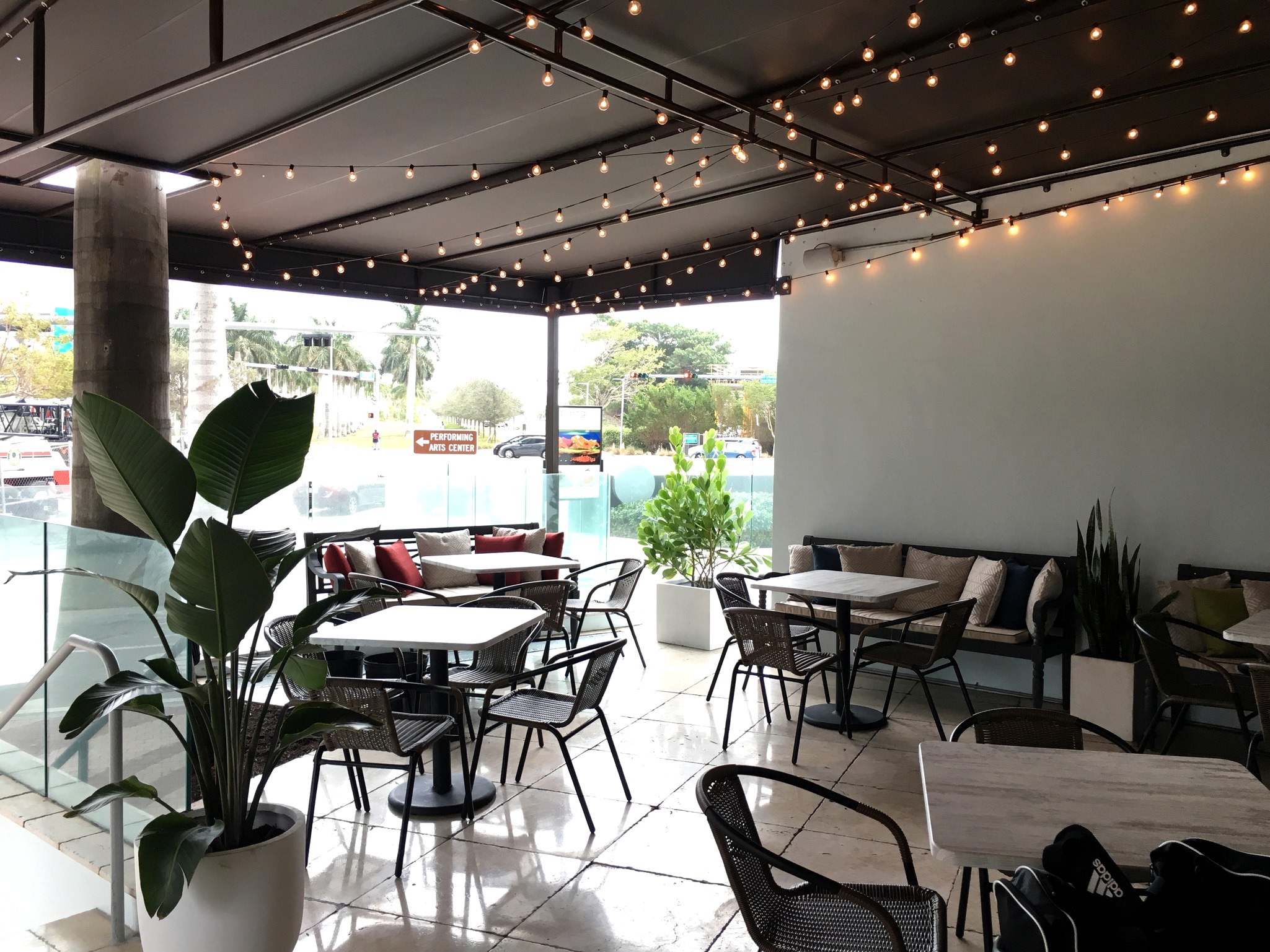 Terraza cubierta de Pairings Restaurant con luces cálidas, vegetación tropical y asientos flexibles