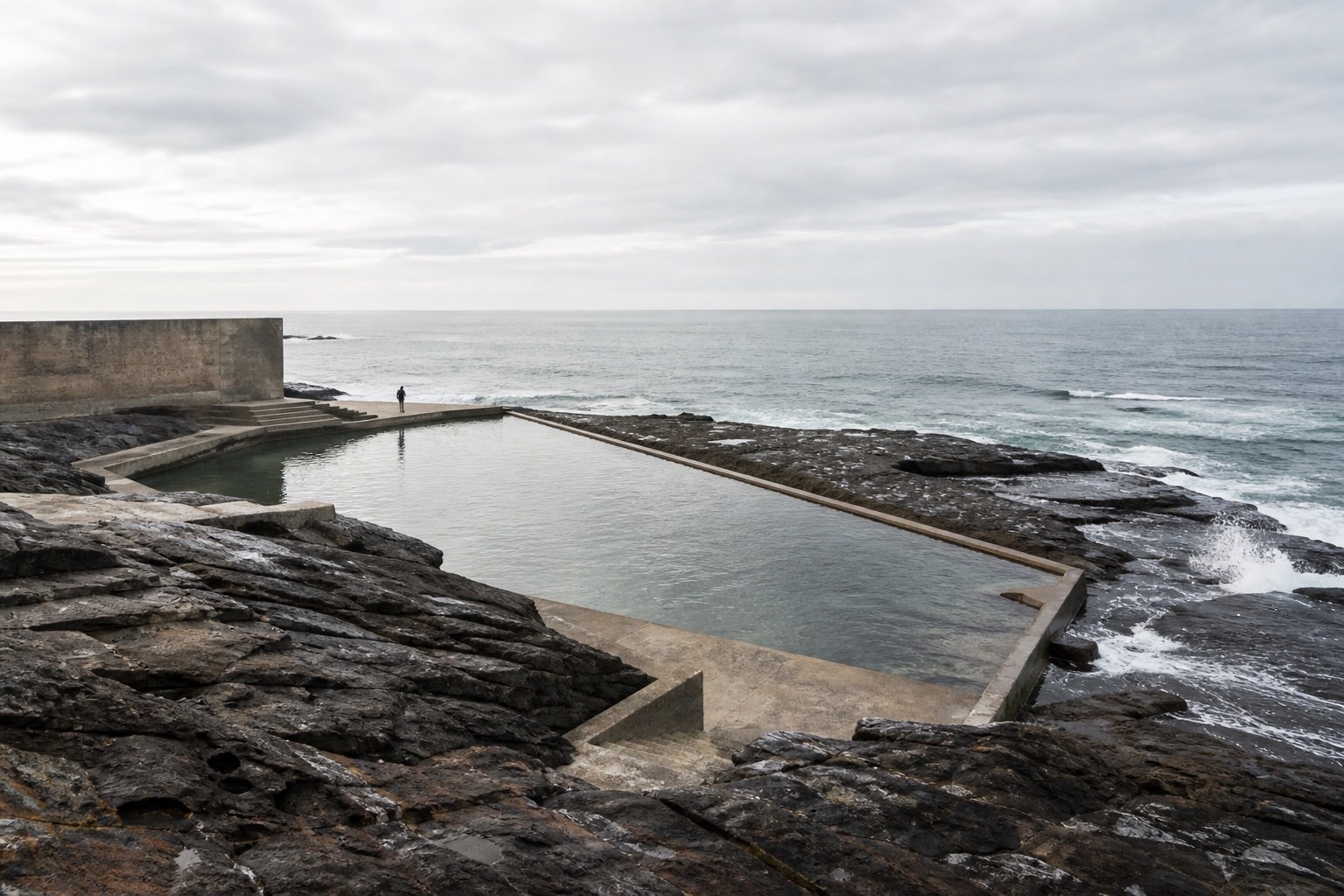 ESSENCE architectural study of water, pale stone, coastal rock and horizon composed as one landscape.