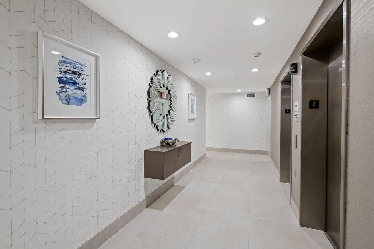 Renovated Casuarina elevator lobby with artwork, mirror, console and layered neutral finishes