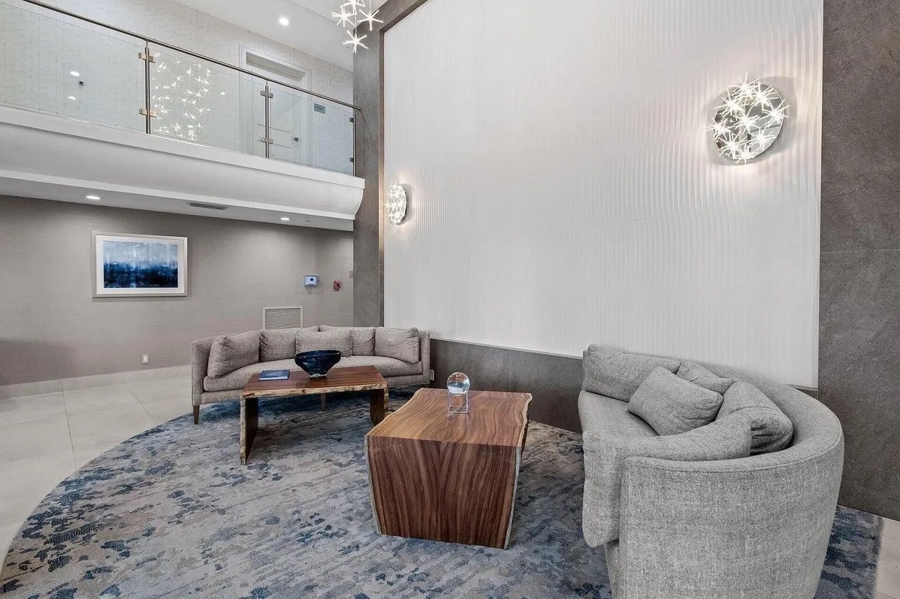 Casuarina lobby lounge with textured wall, neutral seating, live-edge wood tables and sculptural wall lights