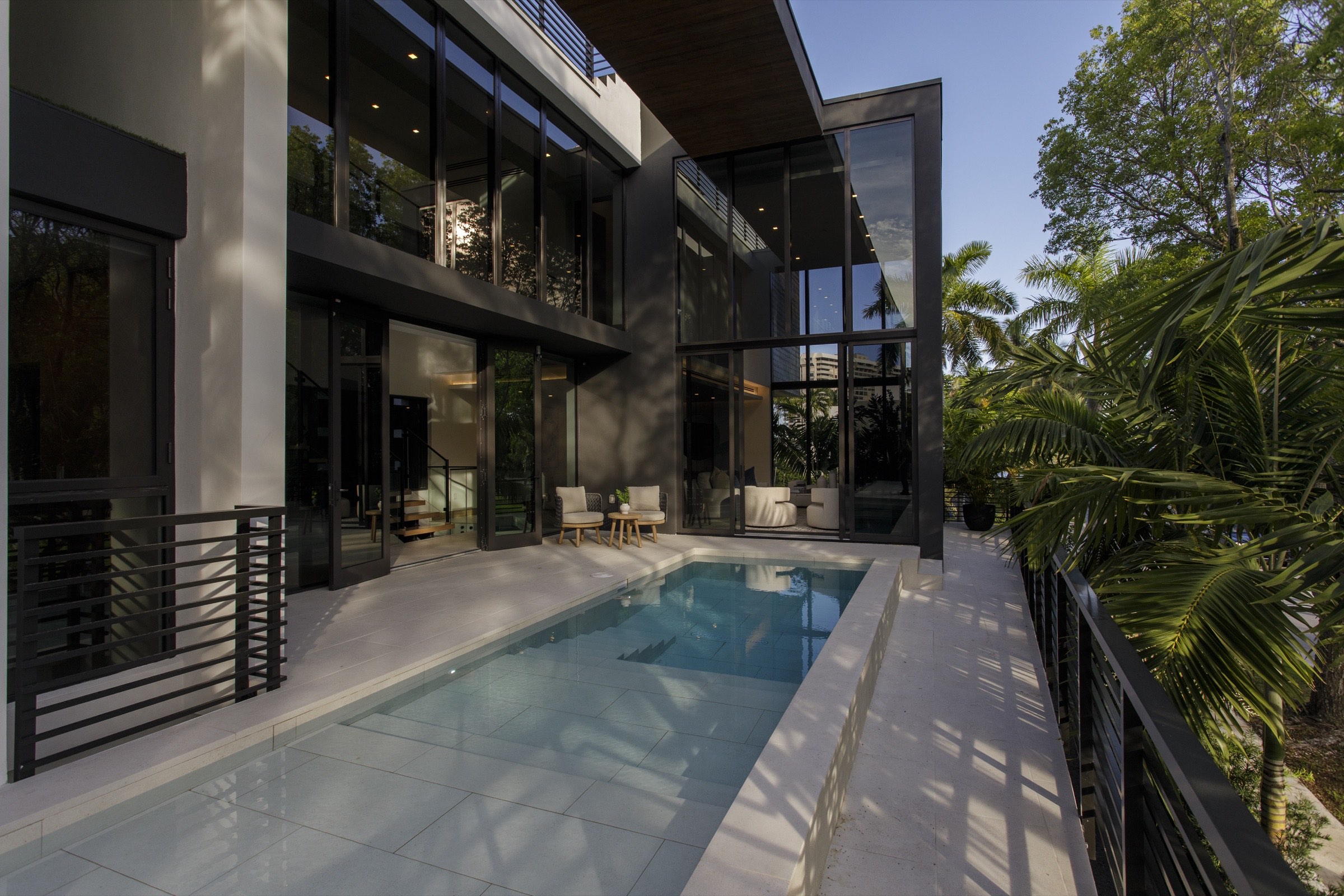 Fair Isle Residence pool courtyard enclosed by living spaces, a shaded terrace and tropical planting in Coconut Grove.