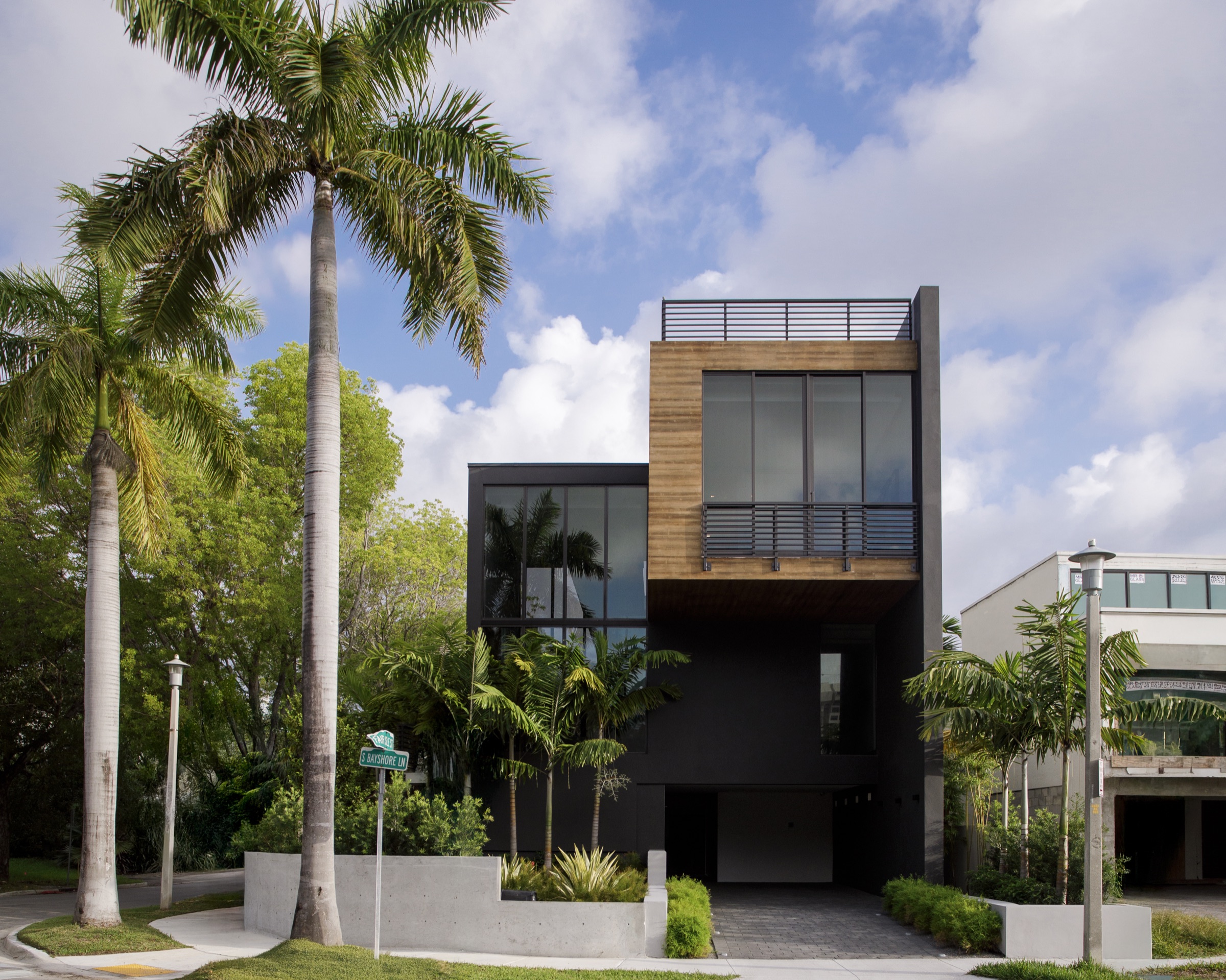 Street facade of Fair Isle Residence framed by mature palms in Coconut Grove