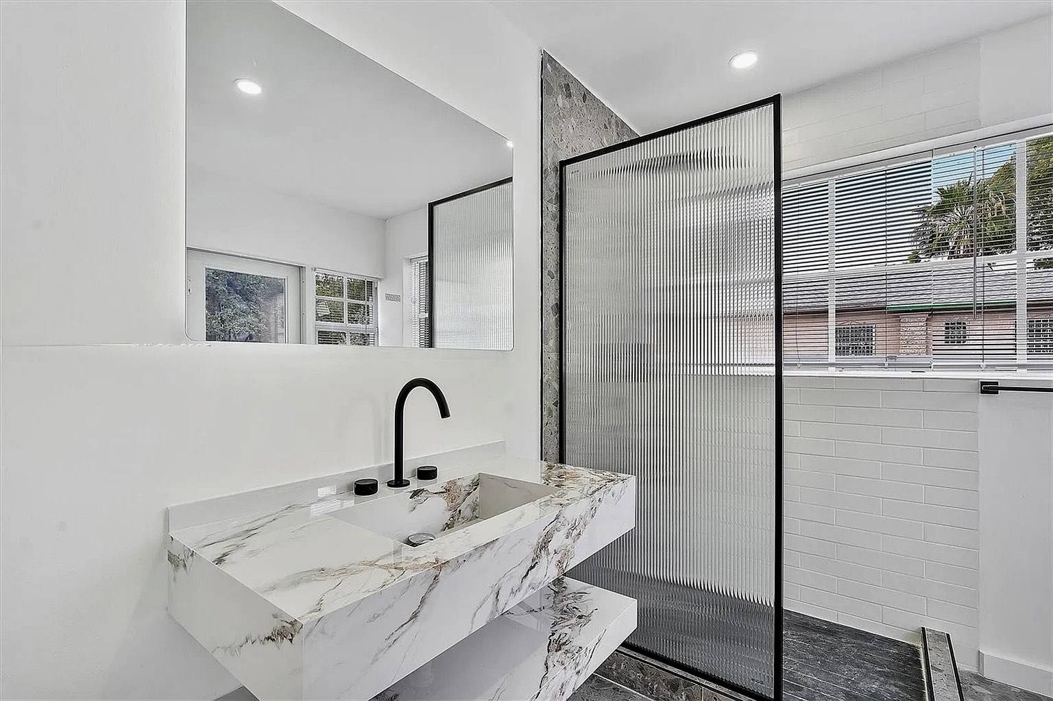 Renovated bathroom at NE 45th Street Residence with marble vanity, integrated lighting and walk-in shower