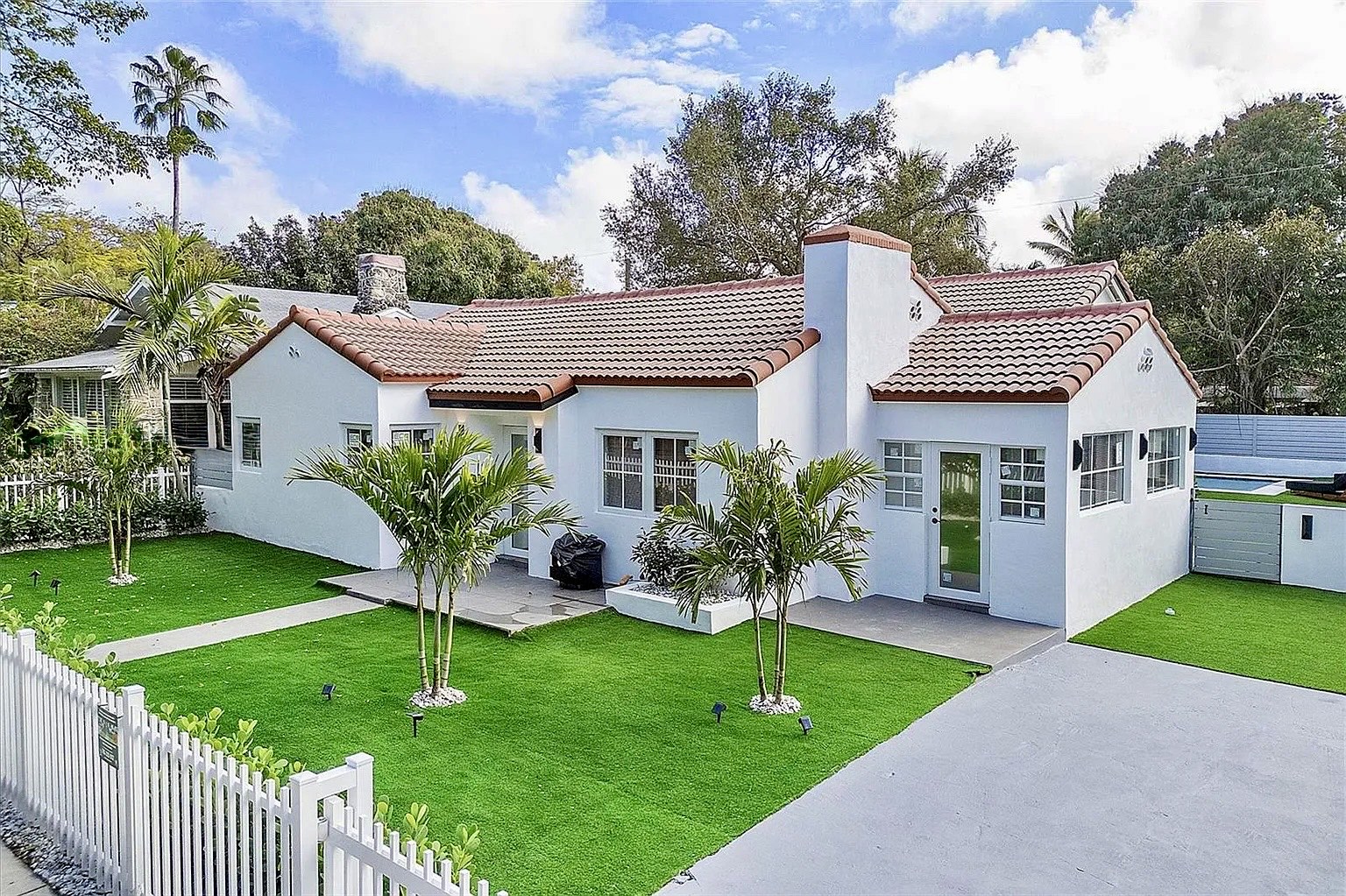 Street-facing view of NE 45th Street Residence with white stucco, tiled roofs and new tropical landscaping